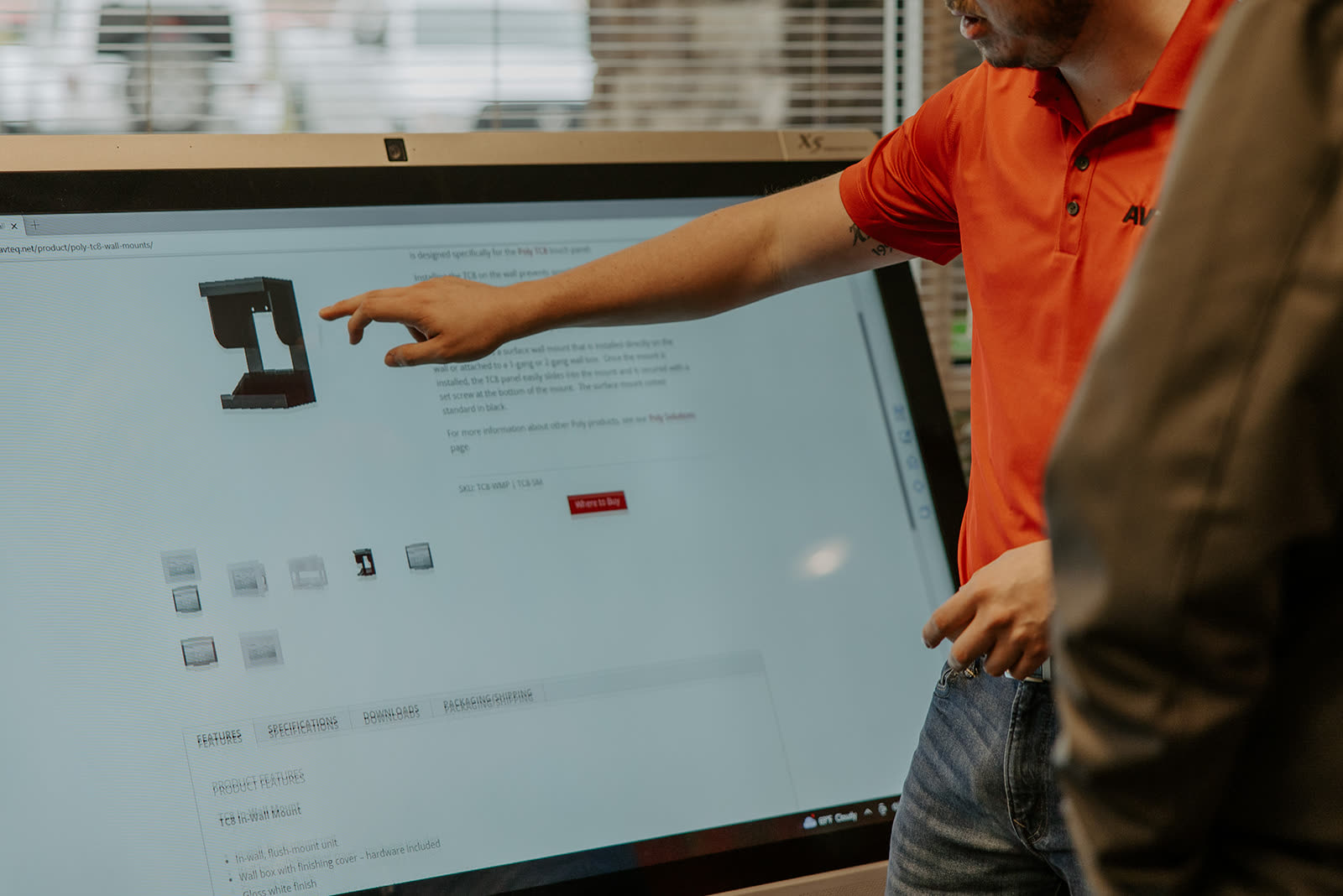 An attendee's hand working an interactive touchscreen up close