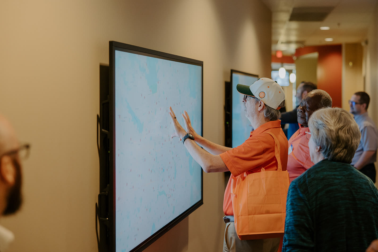 An attendee trying a wall-mounted touchscreen while others watch